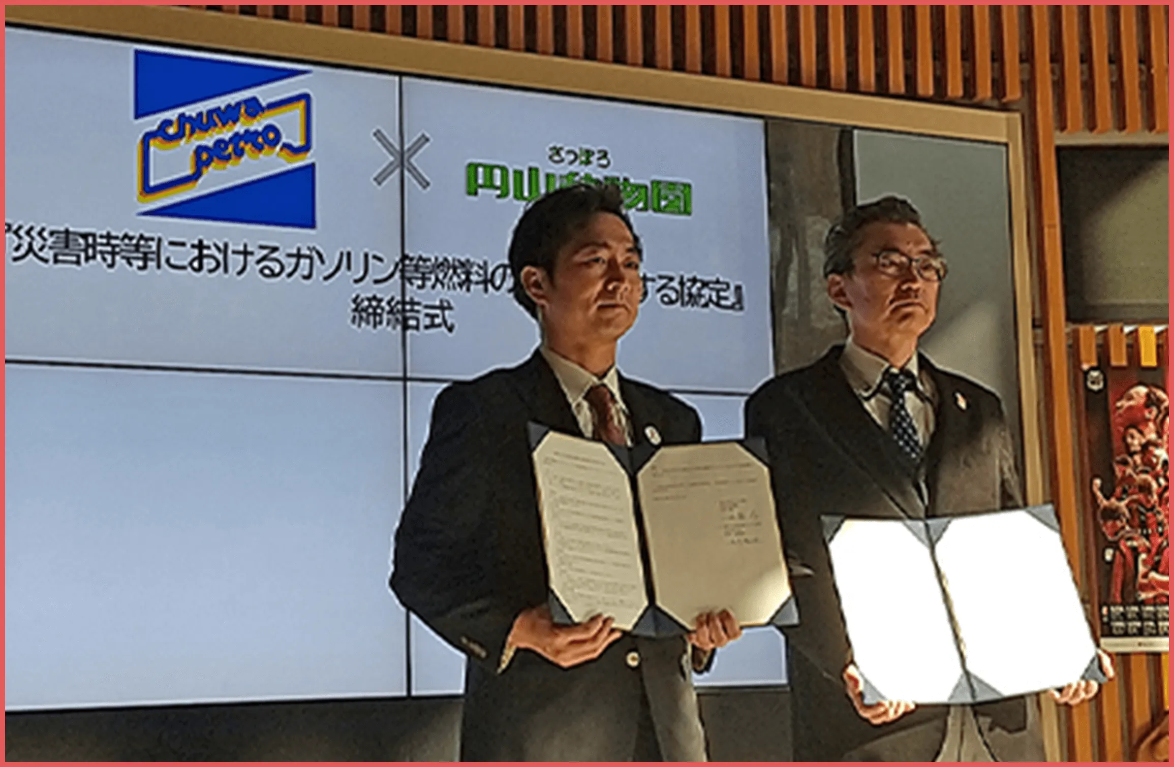 スーツを着た男性が表彰状を持ち立っている画像